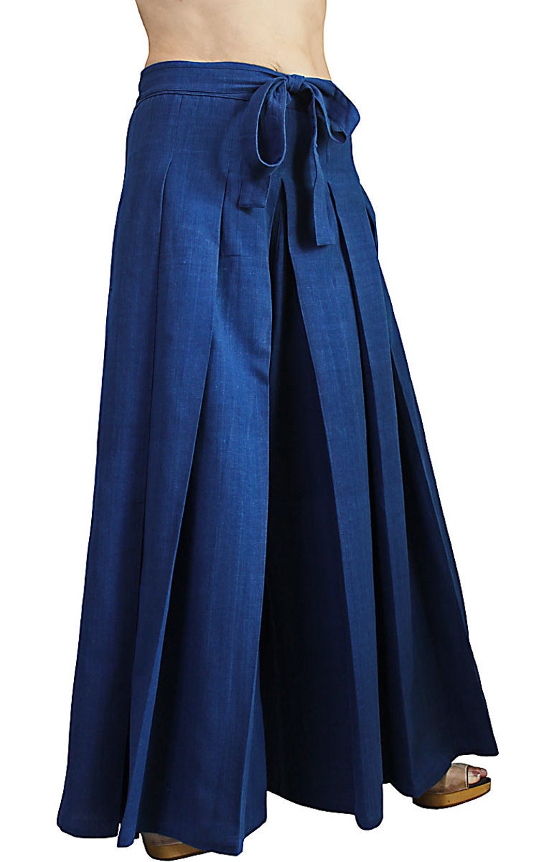 May include: A pair of wide-leg, pleated pants in a deep blue color. The pants have a tie at the waist and are made of a lightweight fabric.