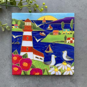 May include: A colorful painting of a lighthouse on a blue ocean with seagulls flying overhead. The lighthouse is red and white with a gold trim. There are houses and trees on the shore. The painting is signed "Malo".