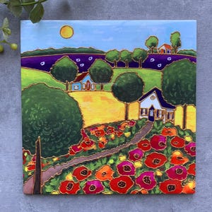 May include: Square painting of a colourful landscape. A sunny sky is above green hills, a field of red and orange flowers, and houses. The artwork shows a path leading to a white house with a blue roof, surrounded by trees and a yellow field.