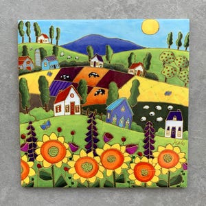 May include: Square ceramic tile with a vibrant countryside scene. The artwork shows green hills, farmhouses, sunflowers, and sheep under a yellow sun. The tile has a glossy finish and is suitable for decorative use, with measurements in centimetres.