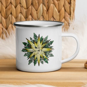 May include: White enamel mug with a silver rim and a handle. The mug features a graphic of a yellow star with green leaves around it.