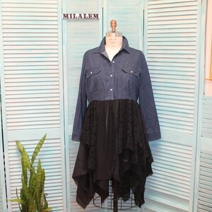 May include: A denim shirt dress with a black lace overlay. The dress has a long sleeve and a button-up front. The lace overlay is layered and asymmetrical.