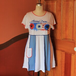 May include: A white dress with blue and white stripes and a red, white and blue graphic of daisies with the text "American Daisies".