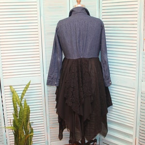 May include: A denim shirt with a black lace overlay skirt. The shirt has long sleeves and a button-up front. The skirt is layered and has a ruffled hem.