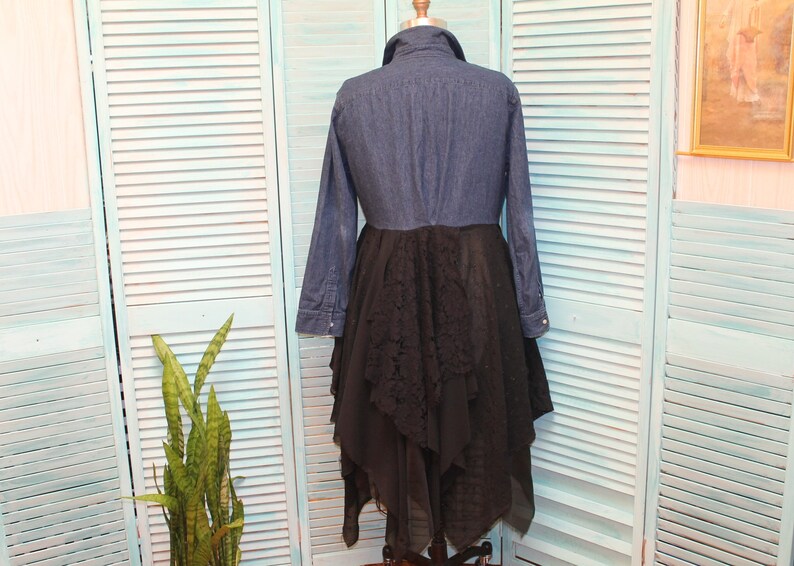 May include: A denim shirt with a black lace overlay skirt. The shirt has long sleeves and a button-up front. The skirt is layered and has a ruffled hem.