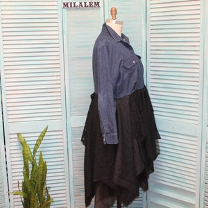 May include: A denim shirt dress with a black lace overlay. The dress has a long sleeve and a button-up front. The lace overlay is layered and asymmetrical.