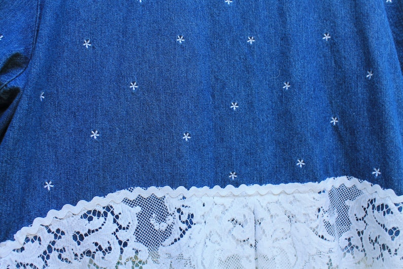 May include: A blue denim skirt with white embroidered stars and a white lace trim.