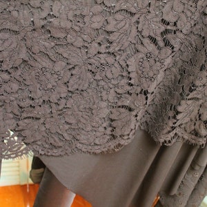 May include: Black lace fabric with a floral pattern. The lace is delicate and intricate, with a soft, flowing texture.