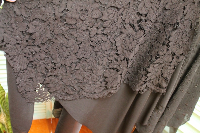 May include: Black lace fabric with a floral pattern. The lace is delicate and intricate, with a soft, flowing texture.