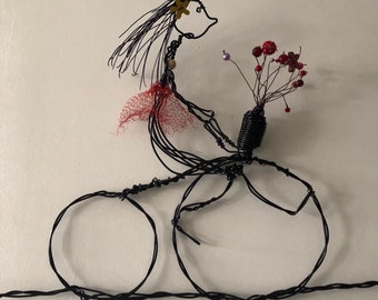 Wire wall hanging. Girl on the bike