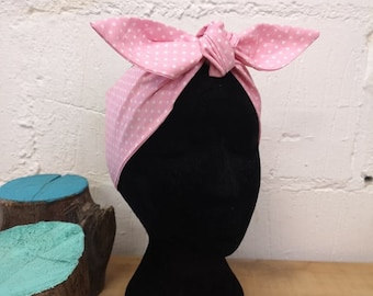 May include: A pink polka dot headband tied in a bow. The headband is on a black mannequin head.