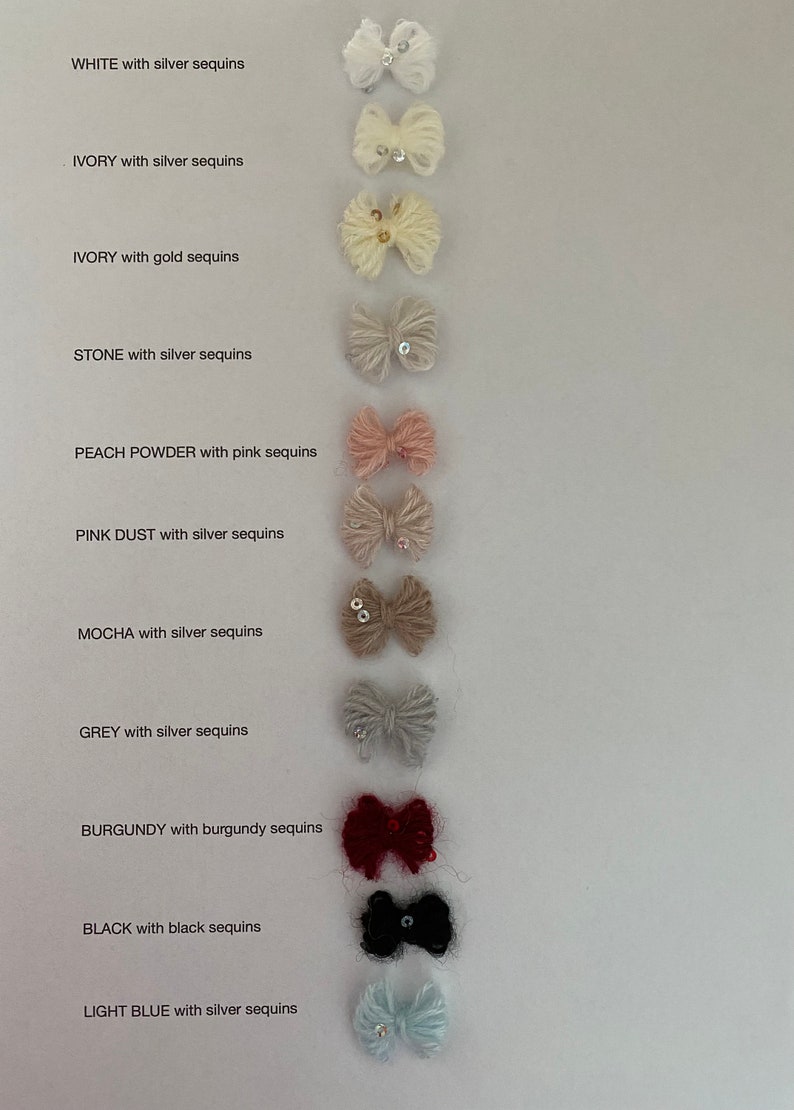 K&ouml;nnte beinhalten: Eine Sammlung kleiner, flauschiger Schleifen in verschiedenen Farben, jede mit Pailletten verziert. Farben sind Wei&szlig;, Elfenbein, Stein, Pfirsichpuder, rosa Staub, Mokka, Grau, Burgunderrot, Schwarz und Hellblau. Der Text zeigt die Farbe und die Farbe der Pailletten an.