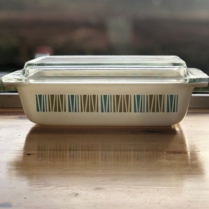 May include: A white rectangular glass baking dish with a clear glass lid. The dish has a geometric pattern of brown and blue stripes.