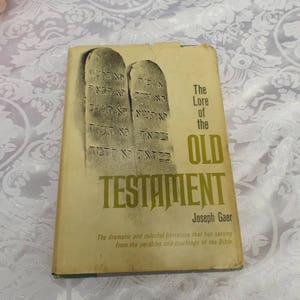 May include: A vintage hardcover book titled "The Lore of the Old Testament" by Joseph Gaer. The book cover features a drawing of two stone tablets with Hebrew writing.