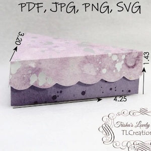 May include: A purple and silver patterned paper box shaped like a slice of cake. The box is 8.13 cm tall, 10.8 cm wide, and 3.63 cm deep. The box is designed for crafts and is perfect for packaging small gifts.
