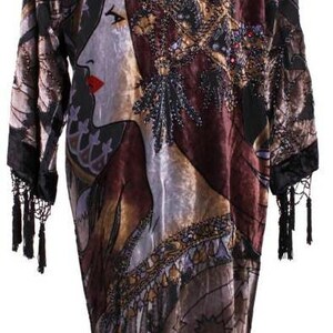 Puede incluir: Una bata larga estampada con el rostro de una mujer y diseños intrincados. La bata presenta una mezcla de colores, incluyendo marrón, dorado y negro, con flecos en el dobladillo y las mangas. El diseño incluye un perfil de mujer y motivos celestiales.