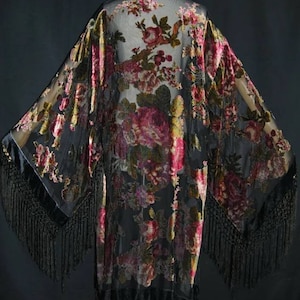 May include: A black sheer kimono with a floral print and black fringe trim. The kimono is made of a lightweight fabric and has a relaxed fit.