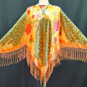 May include: Orange and green peacock print velvet poncho with fringe trim.