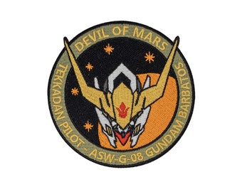 May include: A circular patch with a black background and a yellow and white robot head in the center. The text "DEVIL OF MARS TEKKADAN PILOT - ASW-G-08 GUNDAM BARBATOS" is written around the edge of the patch.