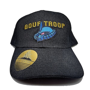 May include: A black baseball cap with a gold embroidered patch that says "GOUF TROOP" and a blue and white cartoon robot head. The cap also has a gold oval patch with the text "DIY ADVENTURES" on the side.