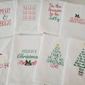 May include: Set of 10 white kitchen towels with red and green embroidered Christmas designs. The designs include "Merry & Bright", "Fa La La La La La", "Tis the Season to be Jolly", "Season's Greetings", "Ho Ho Ho", "Merry Christmas", "Joy Faith Family Ho Ho Ho Christmas Love", and a Christmas tree with the text "To you is born this day in the city of David a Savior who is the Messiah the Lord Luke 2:11".