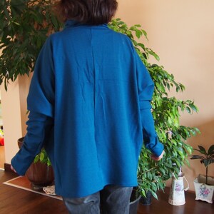 May include: A teal blue oversized sweater with long sleeves and a relaxed fit.