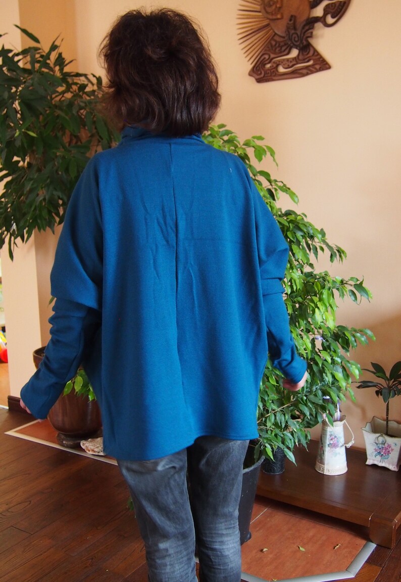 May include: A teal blue oversized sweater with long sleeves and a relaxed fit.