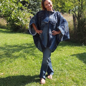 May include: A patchwork denim poncho constructed from various shades of blue denim fabric, featuring a front zipper closure, a high collar, and wide, loose-fitting sleeves. The garment is paired with straight-leg blue denim jeans and open-toe sandals.