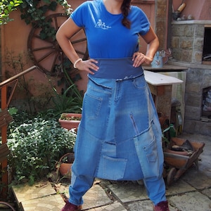 Könnte beinhalten: Ein zweiteiliges Jeans-Ensemble aus Rock und Hose in verschiedenen Blautönen. Der Rock hat mehrere Taschen und einen Reißverschluss. Das Model trägt ein blaues T-Shirt und bordeauxfarbene Sneaker. Eine kreative Interpretation der Jeansmode.