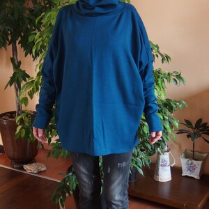 May include: A teal blue turtleneck sweater with long sleeves and a relaxed fit. The sweater is made of a soft, comfortable fabric and is perfect for layering.