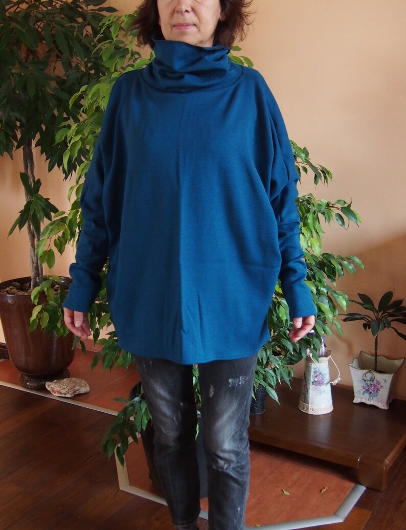 May include: A teal blue turtleneck sweater with long sleeves and a relaxed fit. The sweater is made of a soft, comfortable fabric and is perfect for layering.