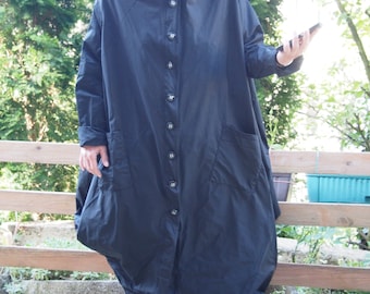 May include: A long, black hooded coat with a button-up front and large pockets. The coat is made of a lightweight fabric and has a relaxed fit.
