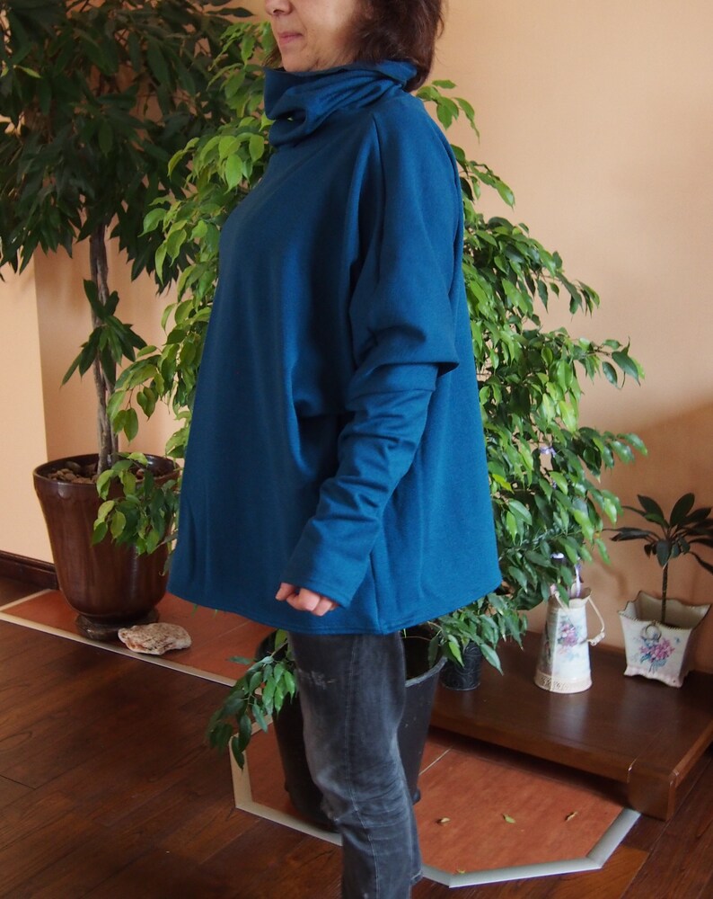 May include: A teal blue oversized sweater with a high neck and long sleeves. The sweater is made of a soft, comfortable fabric and has a relaxed fit.