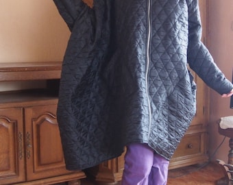 May include: A black quilted jacket with a zipper closure and a hood. The jacket is oversized and has a diamond pattern. The person wearing the jacket is also wearing purple pants and brown boots.
