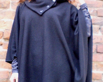 May include: A black poncho with a high collar and button closure. The poncho is made of a soft, warm fabric and is perfect for layering in the fall or winter.