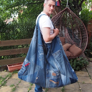 May include: A large hobo-style shoulder bag constructed from repurposed blue denim jeans. The bag features a patchwork design incorporating various shades of blue denim, visible pockets, metal rivets, and stitched seams throughout the fabric surface.