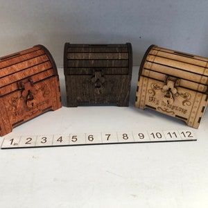 May include: Three wooden treasure chests with a hinged lid and a lock. The chests are stained in different shades of brown. The chests are approximately 4 inches wide and 3 inches tall. The chests are labeled "My Treasures" and "Big Adventures".