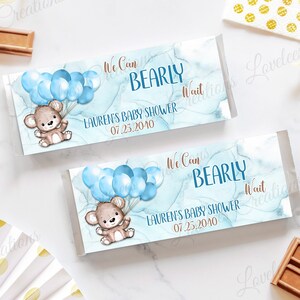 May include: Two blue and white watercolor-style baby shower favor tags with a cute cartoon bear holding blue balloons. The text on the tags reads "We can barely wait" and "Lauren's Baby Shower 07.25.2040".