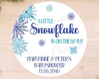 May include: A white circle with blue snowflakes and the text "A Little Snowflake Is On The Way!"  Maryanne & Peter's Baby Shower 12.05.2040