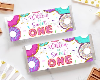 May include: Two printable chocolate bar wrappers with a donut theme. The wrappers are white with pink, purple, blue, and green donuts with sprinkles. The text on the wrappers reads "Willow is a Sweet One".