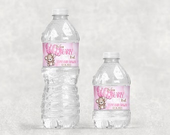 May include: Two clear plastic water bottles with pink and gold labels. The labels feature a cartoon bear holding pink balloons and the text "We're Bearly Wait" and "Stephe's Baby Shower 02.26.2023".