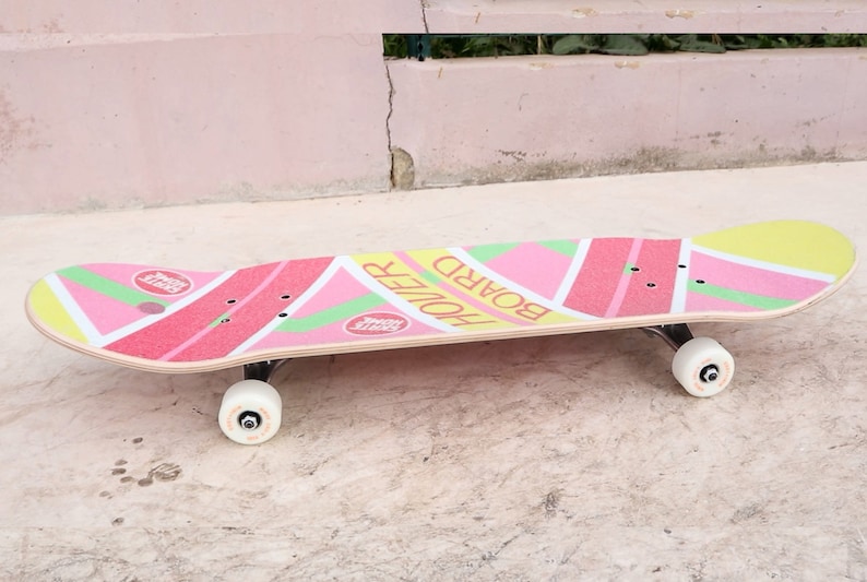 May include: A pink, yellow, and green skateboard with the words "Board Holler" printed on the deck.