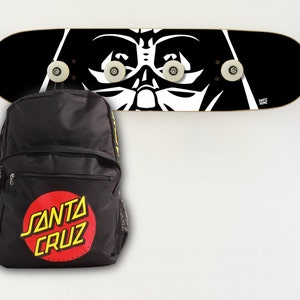 May include: A black backpack with a red and yellow Santa Cruz logo. A black and white skateboard with a Darth Vader graphic is hanging on the wall behind the backpack.