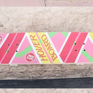 May include: A pink, yellow, and green skateboard with the words "Hover Board" printed on it. The board has two red circles with the words "Skate Home" printed on them.