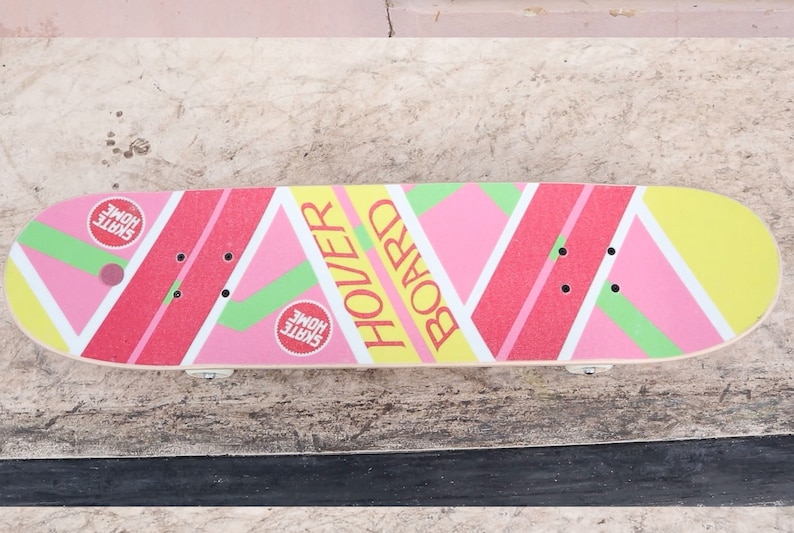May include: A pink, yellow, and green skateboard with the words "Hover Board" printed on it. The board has two red circles with the words "Skate Home" printed on them.