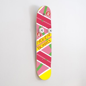 Puede incluir: Una patineta rosa y amarilla con las palabras "Hover Board" impresas en ella. La patineta tiene rayas verdes y dos ruedas blancas.