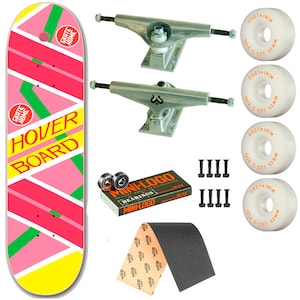 Puede incluir: Una tabla de skate rosa, verde y amarilla con las palabras "Skate Home" y "Hover Board" impresas en ella. La tabla viene acompañada de un juego de ejes plateados, ruedas negras, rodamientos negros, herrajes negros y una cinta de agarre negra.