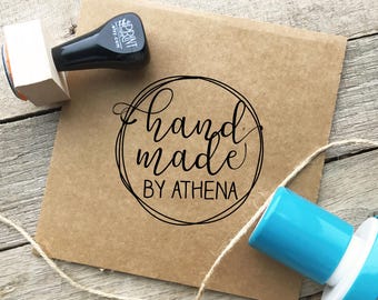 May include: A brown paper package with a black and white "Handmade by Athena" stamp. Two stamps, one black and one blue, are visible. A length of twine is also present.