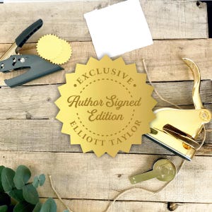 May include: A gold-colored seal with the text "EXCLUSIVE Author Signed Edition ELLIOTT TAYLOR" is displayed. A gray and black seal press, a key, and a blank white paper are also present. The items are arranged on a wooden surface.