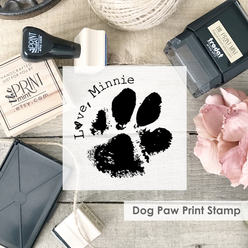 A graphic of a dog paw print is superimposed over a photo of wood mounted and self-inking rubber stamps.  To the top left of the paw is text which reads Love Minnie, with the O in the shape of a heart.